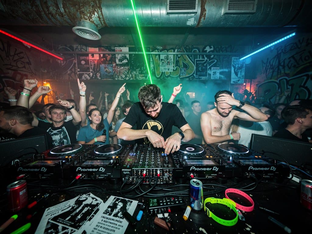 Leerer Techno-Club mit Anti-AI-Graffiti und analogem DJ-Setup